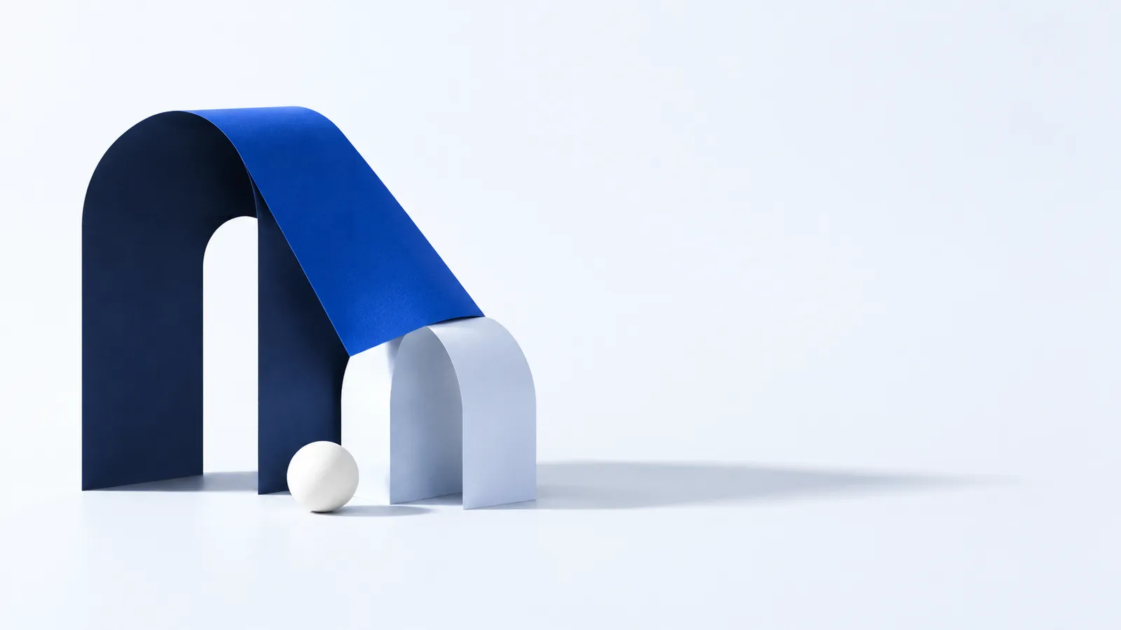 Two paper arches, one tall and navy, one small and pale, joined by a cobalt canopy fold.